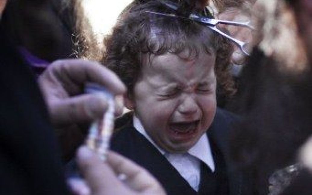 Ізраїль, Мерон. Трирічний єврейський хлопчик плаче під час участі у традиційній церемонії ультра ортодоксальних євреїв &mdash; опшернеш (халаке), коли хлопчикам вперше обстригають волосся. / © AFP