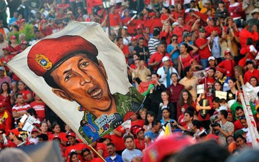 Венесуела, Каракас. Прихильники президента Венесуели Уго Чавеса тримають прапор з його портретом під час святкування його повернення з Куби. Чавес повернувся до Венесуели після трьох тижнів лікування на Кубі, де йому видалили ракову пухлину. / © AFP