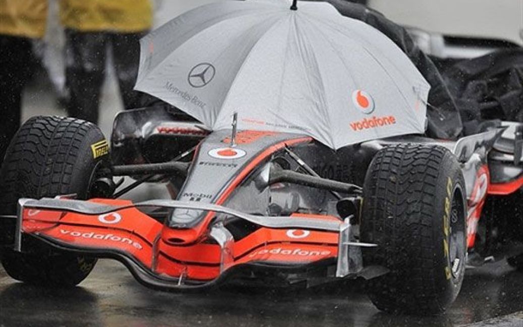 Австралія, Мельбурн. Гонщик Формули-1 ховається під парасолькою від проливного дощу напередодні перегонів на Гран-прі Австралії в Мельбурні. / © AFP