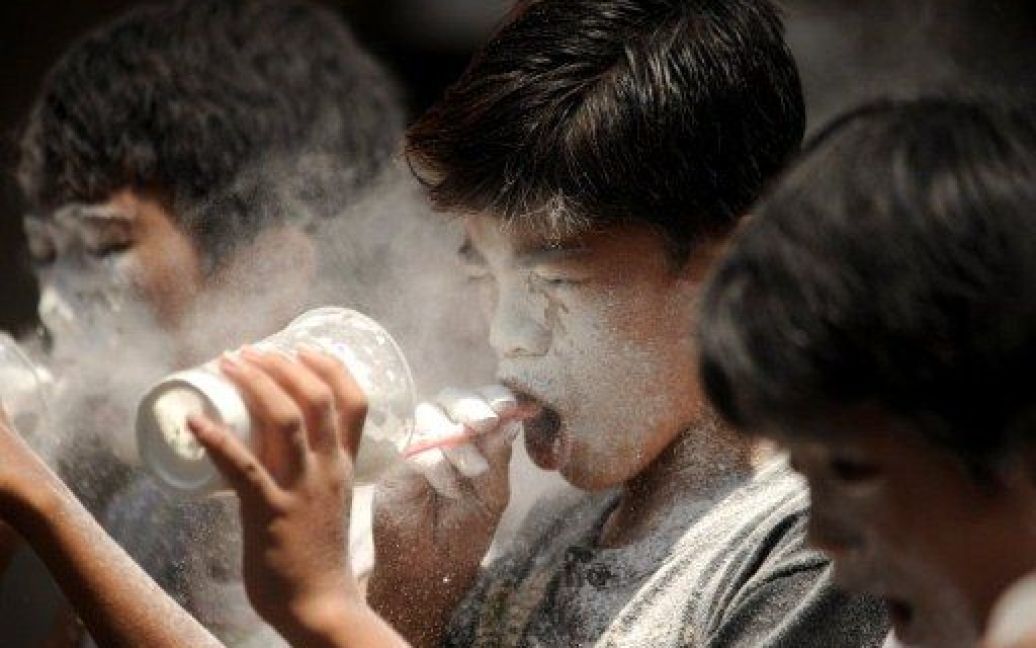 Філіппіни, Маніла. Філіппінські діти намагаються видмухнути борошно зі склянок через соломинки під час гри на щорічному святі, Дні Святої Рити у передмісті Маніли. / © AFP