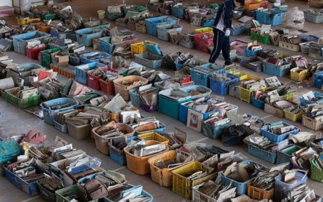 Японія, Наторі. Чоловік шукає свої фотографії серед речей, які були зібрані добровольцями у смітті та уламках будинків в місті Наторі, префектура Міягі. / © AFP