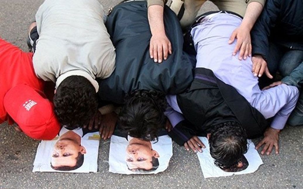 Ліван, Бейрут. Сірійці, які працюють в Лівані, стоять на колінах і цілують фотографії свого президента Башара аль-Асада під час проурядового мітингу перед посольством Сирії в Бейруті. / © AFP