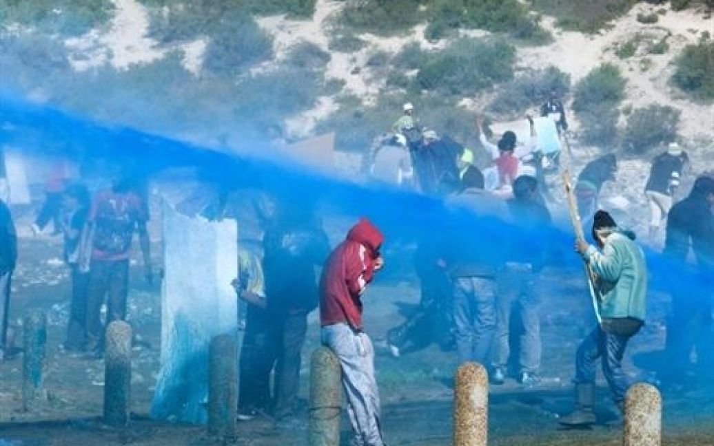 ПАР, Кейптаун. Поліція розпилює синю суміш, воду і сльозоточивий газ на скваттеров, які вирішили побудувати свої будівлі на відкритій ділянці землі. / © AFP