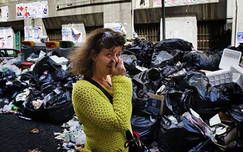 Італія, Неаполь. Жінка закриває носа, коли вона проходить повз купи сміття на вулиці в районі Поццуолі, передмісті Неаполя. Італійські солдати прибули до Неаполя, щоб почати очищення міста від сміття, якого там назбиралось більше 4 тисяч тонн. / © AFP