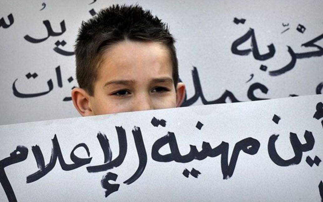 Греція, Афіни. Дитина стоїть за плакатом із написом арабською: "Де професіоналізм ЗМІ?" під час демонстрації сирійських громадян, які проживають у Греції, перед посольством Сирії в Афінах. Учасники акції закликали свою країну до свободи. / © 
