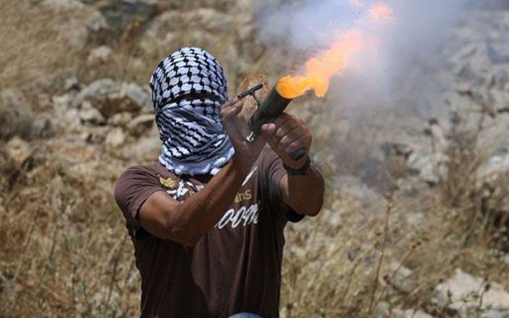 Нілін. Палестинський юнак кидає імпровізований вибуховий пристрій зі сльозоточивим газом у ізраїльських солдатів, які розганяють молодь під час сутичок після демонстрації проти ізраїльських поселень і розділової стіни в селищі Нілін. / © AFP