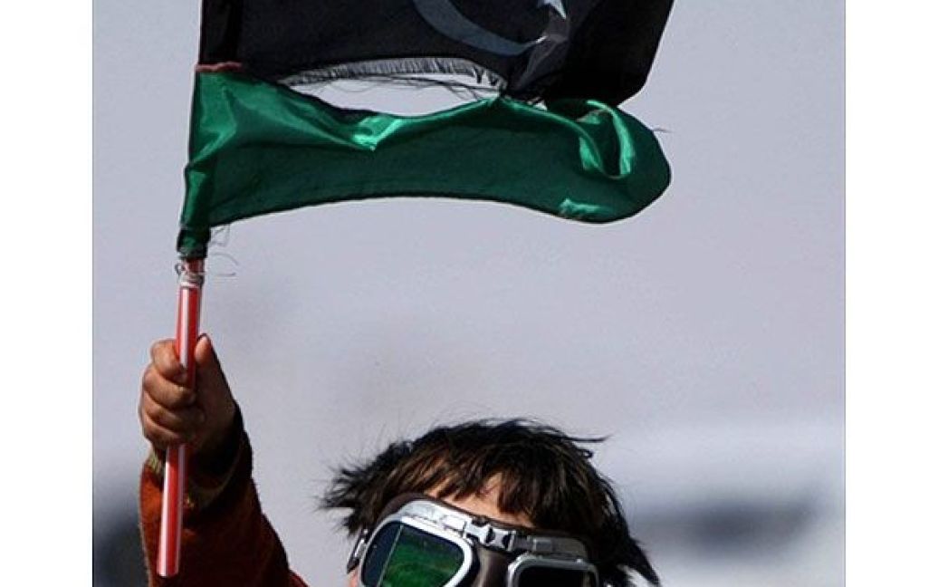 Лівійська Арабська Джамахірія, Аждабія. Лівійський хлопчик розмахує прапором повстанців. Офіційні представники повстанської Тимчасової національної ради заявили, що близько 10000 людей вже були вбиті військами Муаммара Каддафі. / © AFP