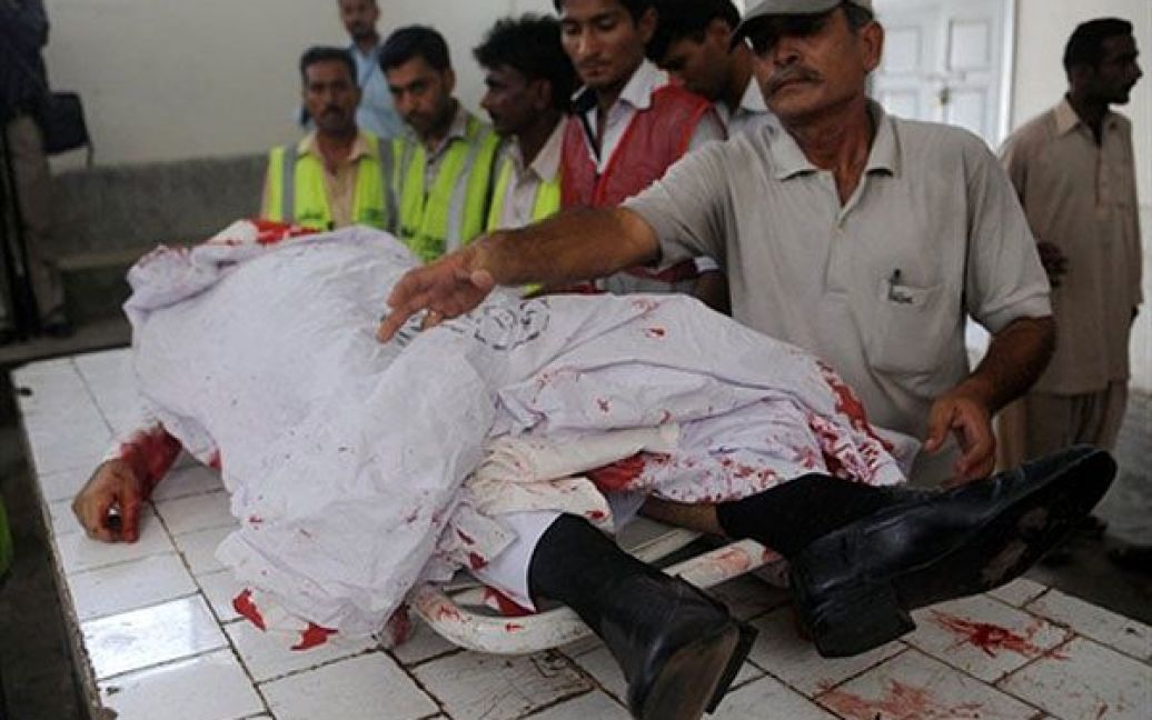 Пакистан, Карачі. Пакистанці оглядають труп саудівського дипломати, якого розстріляли четверо невідомих на мотоциклах. Дипломат помер від вогнепальних поранень на місці. / © AFP