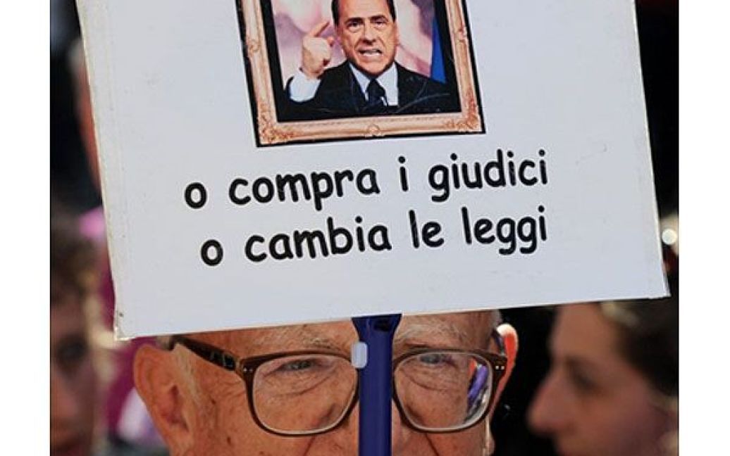 Італія, Рим. Учасник акції протесту тримає плакат "Або ви купуєте суддів, або змінюєте закон" під час демонстрації перед парламентом Італії, де голосували проти можливості суду Мілана проводити судовий розгляд сексуальних злочинів італійського прем&#039;єр-міністра Сільвіо Берлусконі. / © AFP