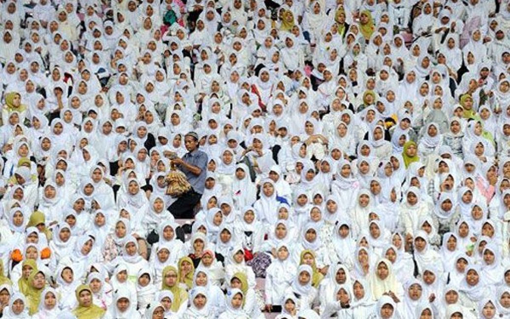 Індонезія, Джакарта. Продавець йде через натовп індонезійських жінок, які зібрались на церемонію, присвячену 85-річчю організації Нахдлатул Улама, в Джакарті. Ця організація є найбільшою мусульманською організацією в Індонезії і однією з найбільших незалежних ісламських організацій в світі, яка нараховує більше 50 млн членів. / © AFP