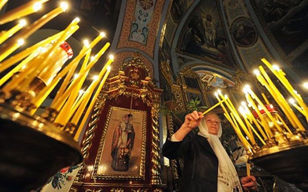 Україна, Чорнобиль. Жінка запалює свічку під час православного пасхального богослужіння в місті Чорнобиль. / © AFP