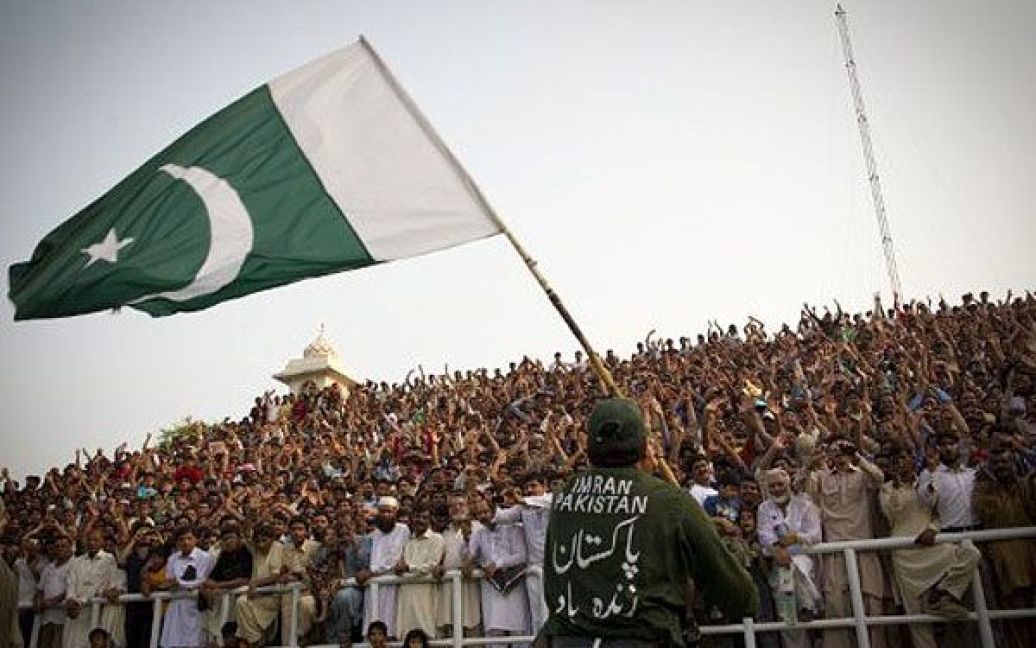 Пакистан, Вага. Пакистанець розмахує прапором перед глядачами, які відвідали щоденну церемонію спущення прапорів Пакистану та Індії на кордоні в місті Вага. Через Вагу проходить єдина дорога, яка перетинає кордон між Індією і Пакистаном. / © AFP