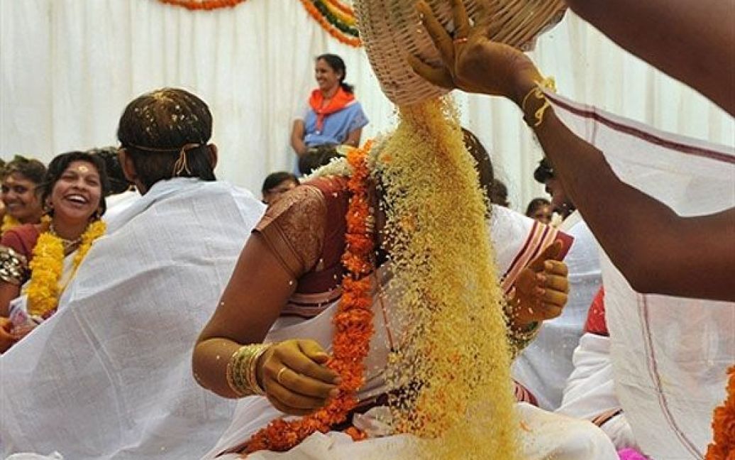 Індія, Хайдарабад. Індійські наречені посипають один одного рисом на знак процвітання під час церемонії масового весілля, в якій взяли участь 175 пар, у Хайдарабаді. / © AFP