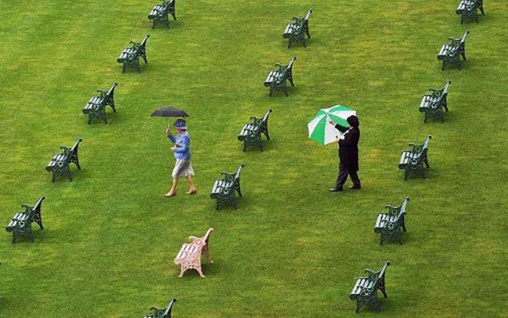 Великобританія, Аскот. Відвідувачі щорічних королівських скачок Royal Ascot з парасольками проходять між лавками під час четвертого дня перегонів. П&#039;ятиденні скачки в Аскоті є однією з найяскравіших подій року. / © AFP