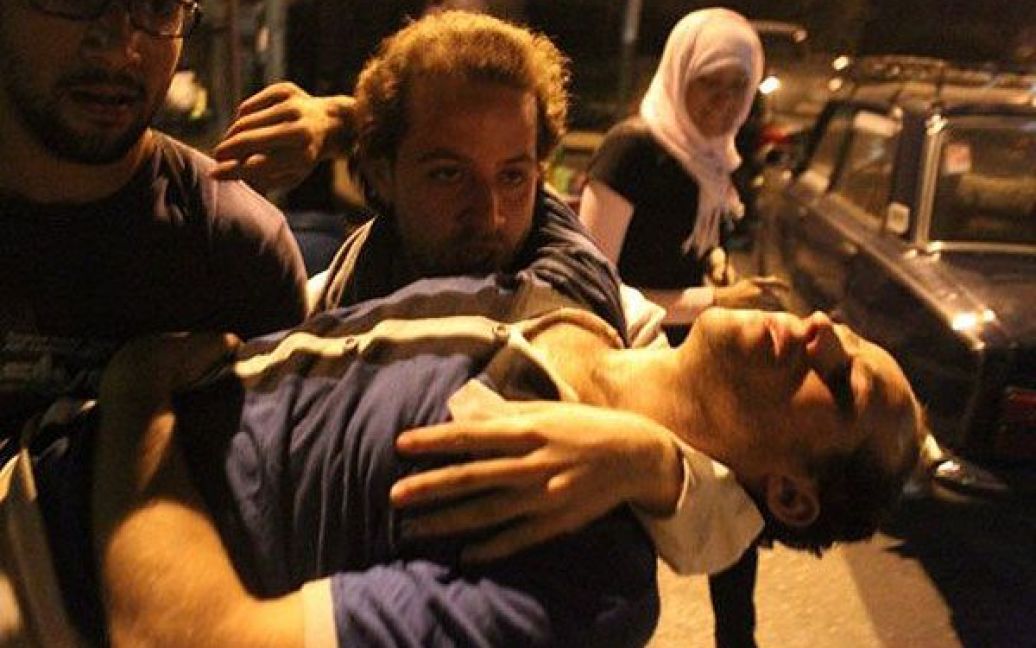 Єгипет, Каїр. Єгипетські демонстранти несуть поранених під час зіткнень з поліцією на площі Тахрір у Каїрі. Сили безпеки Єгипту застосували сльозогінний газ проти демонстрантів в ході запеклих зіткнень. / © AFP