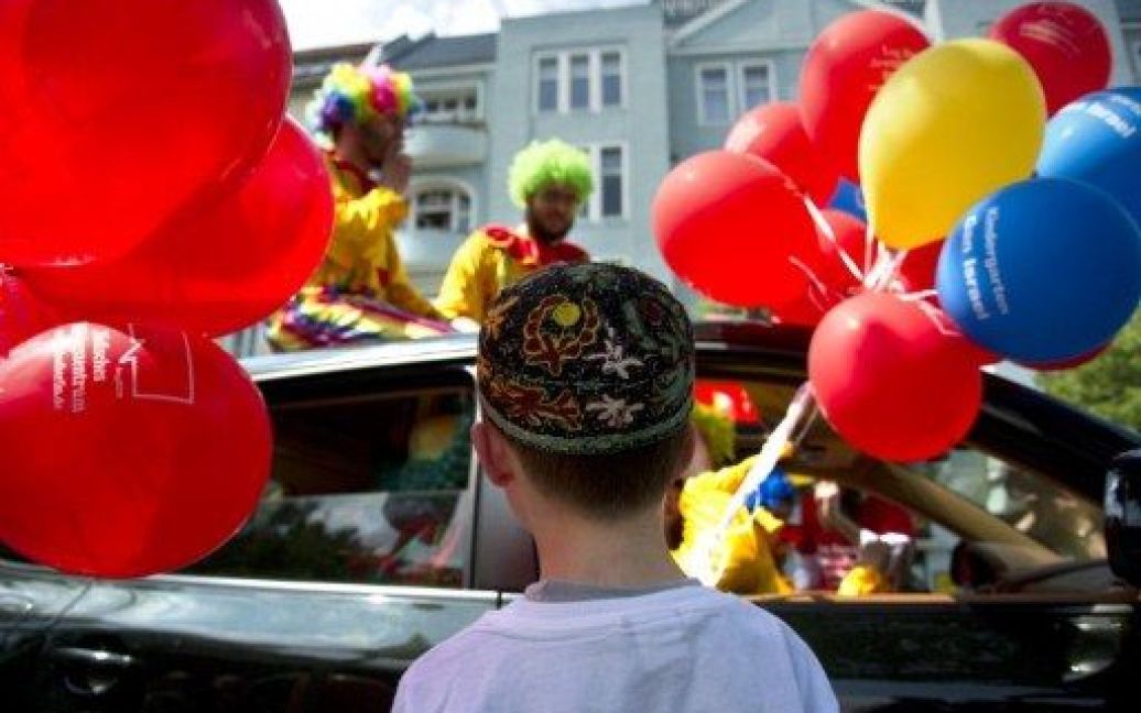 Німеччина, Берлін. Хлопчик дивиться на платформу з клоунами, які беруть участь у святкуванні єврейської громади, що провела парад за мир та взаєморозуміння. / © AFP