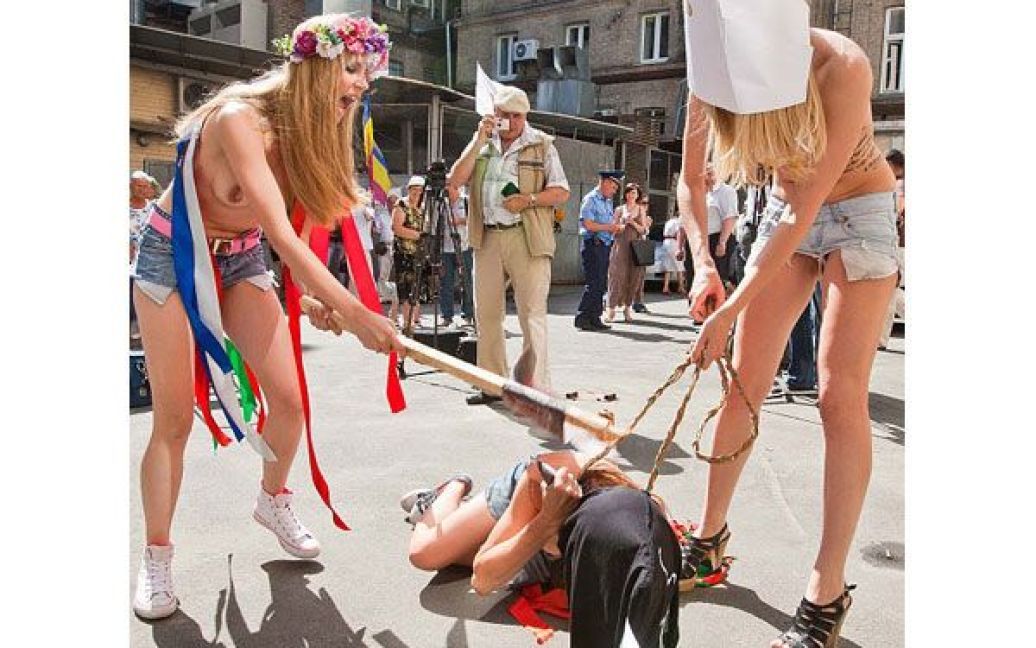 Оголені дівчата з руху FEMEN у ковпаку ката та з макетом сокири в руках почали імітувати страту з криками "Забій кролятини". / © 
