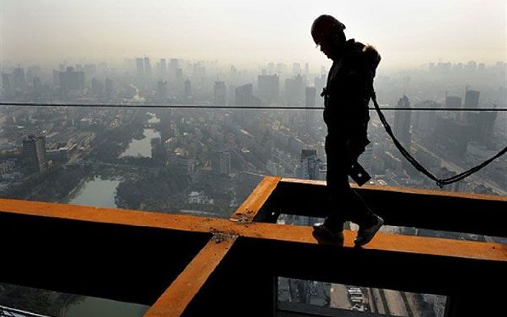 Китай, Хефей. Китайський робітник працює на висотному будівництві у Хефеї, провінція Аньхой. Китай заявив, що економіка країні постійно зростає, але повільнішими темпами, ніж минулого року. / © AFP