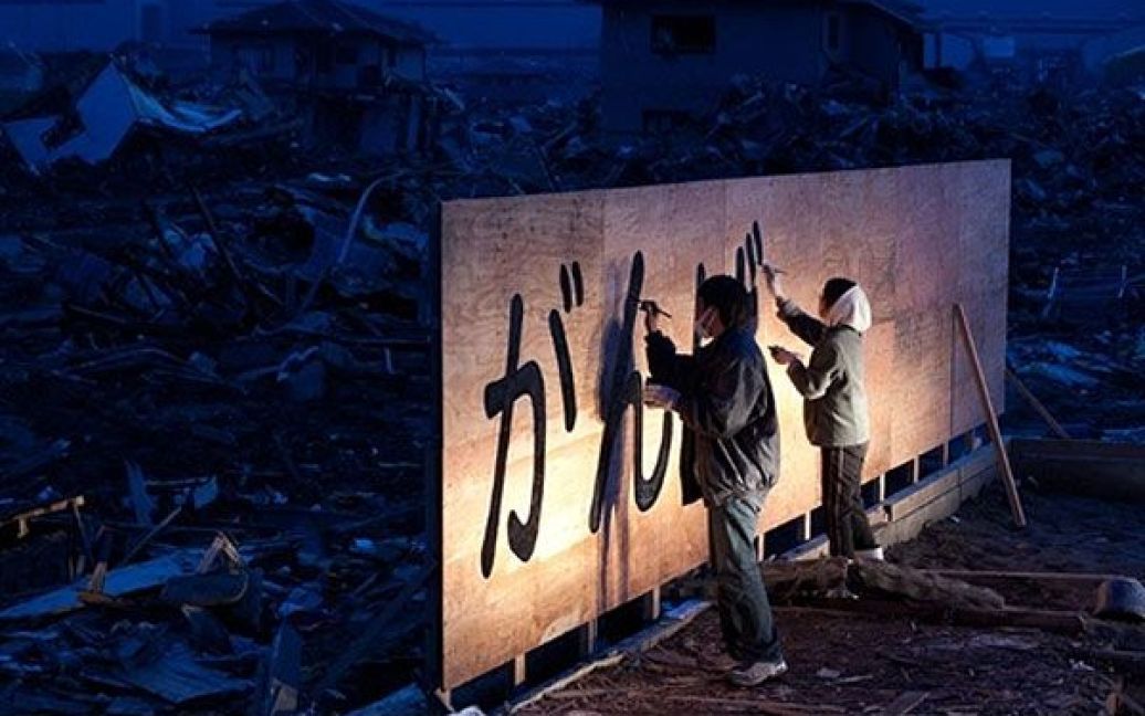 Японія, Ісіномакі. Тадао Камеі та його товариш пишуть "Тримайтеся!" на новому білборді у місті Ісіномакі, префектура Міягі. Прем&#039;єр-міністр Наото Кан пообіцяв, що "ніколи не покине на призволяще" жертв землетрусу та цунамі в Японії. / © AFP