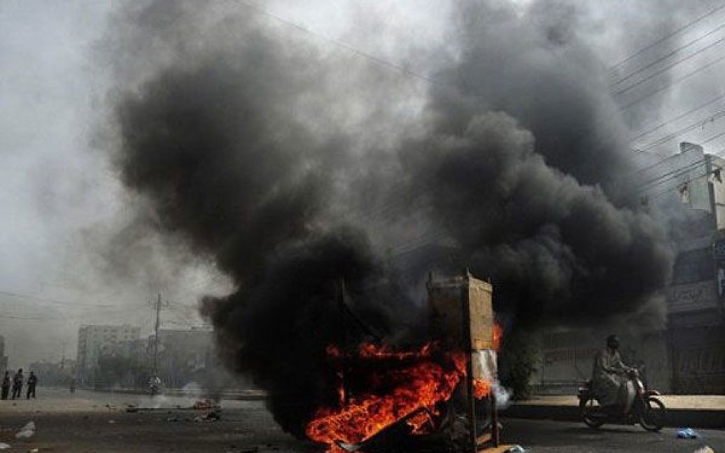 Пакистан, Карачі. Пакистанець проїздить повз купу палаючих шин і меблів після сутичок і спалаху насильства на околиці Карачі. / © AFP