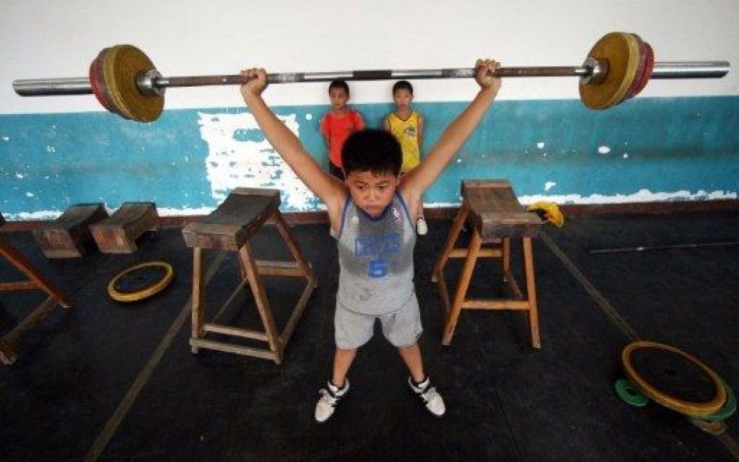 Китай. Китайський хлопчик бере участь у тренуванні з важкої атлетики в училищі важкоатлетів у південній провінції Фуцзянь. Молоді китайці часто вступають у спортивні школи в надії на майбутні медалі. / © AFP