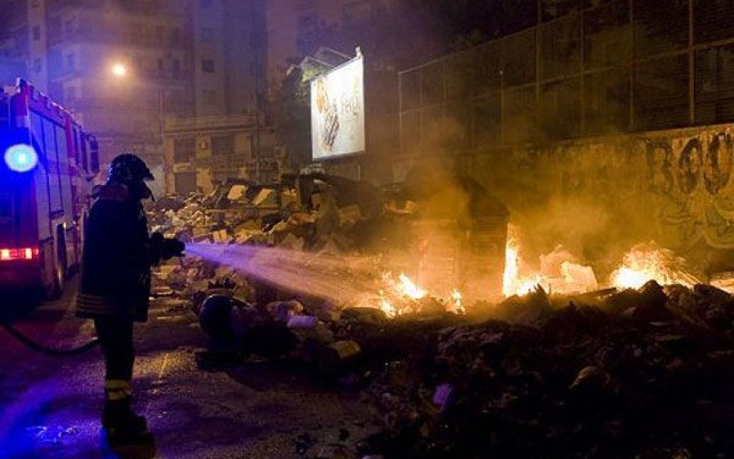 Італія, Неаполь. Пожежний гасить палаючу купу сміття в центрі Неаполя. Італійських військових направили до Неаполя, щоб вони допомогти очистити місто від сміття. / © AFP