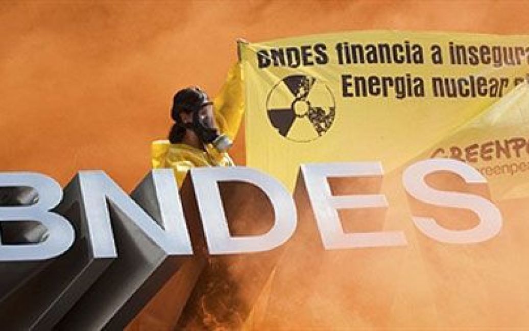 Бразилія, Ріо-де-Жанейро. Активісти екологічного руху Грінпіс підпалюють жовті димові шашки під час акції протесту перед Національним банком розвитку (BNDES) в Ріо-де-Жанейро. Активісти виступили проти фінансування будівництва нових АЕС поблизу Ріо-де-Жанейро. / © AFP