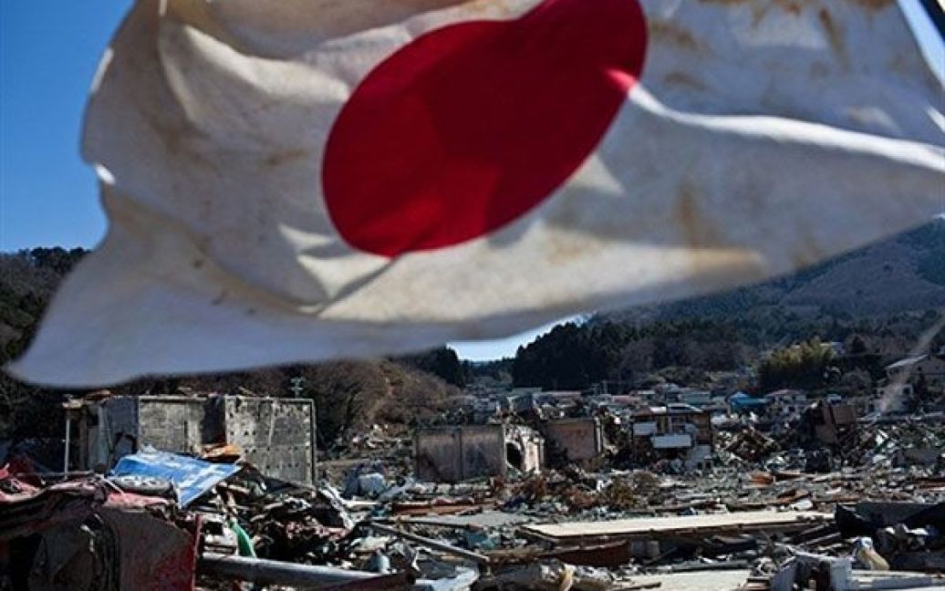 Японія, Онагава. Японський прапор вивішено на тлі уламків у зруйнуваному цунамі місті Онагава, префектура Міягі. Сотні тисяч людей були змушені покинути свої будинки і знайшли притулок у тимчасових таборах. / © AFP
