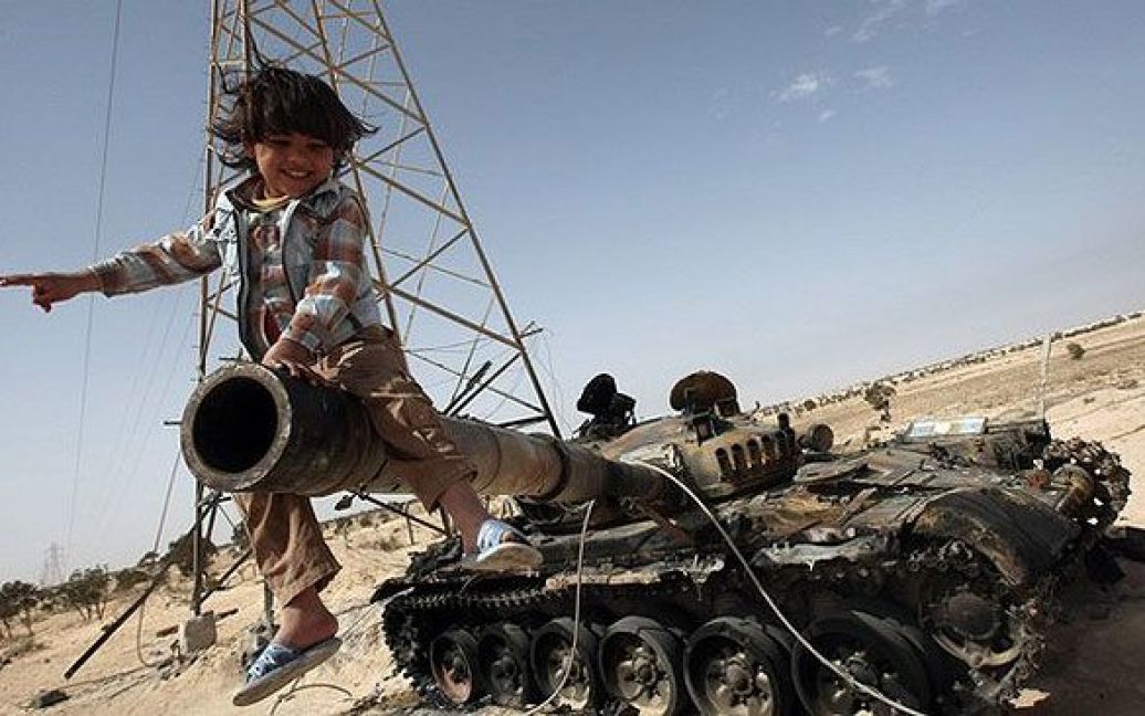 Лівійська Арабська Джамахірія, Аждабія. Лівійська дитина сидить на гарматі підбитого танку у місті Аждабія. Міжнародні сили зібралися в Лондоні, щоб намітити "майбутнє після Каддафі" для Лівії. / © 