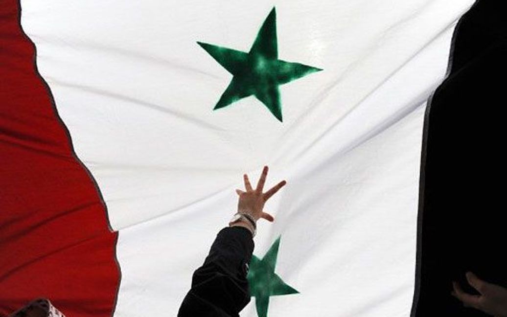 Туреччина, Стамбул. Жінка тримає сирійський прапор під час демонстрації сирійців, що проживають у Туреччині, проти режиму президента Сирії Башара аль-Асада. Сили Асада вбили щонайменше 1486 цивільних осіб під час боротьби з повстанням, що почалось в Сирії у березні 2011 року. / © AFP