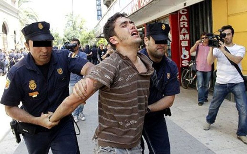 Іспанія, Валенсія. Поліцейські затримують юнака під час акції протесту перед входом до регіонального парламенту у Валенсії. Вісім поліцейських отримали поранення, п&#039;ятеро демонстрантів були заарештовані в ході зіткнень, які спалахнули під час акції протесту проти економічної кризи і безробіття. / © AFP