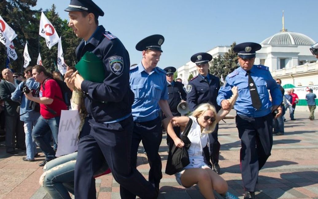 Через кілька секунд після початку топлес-акції протесту працівники міліції взяли дівчат за руки та ноги і віднесли до міліцейських автобусів. / © Жіночий рух FEMEN