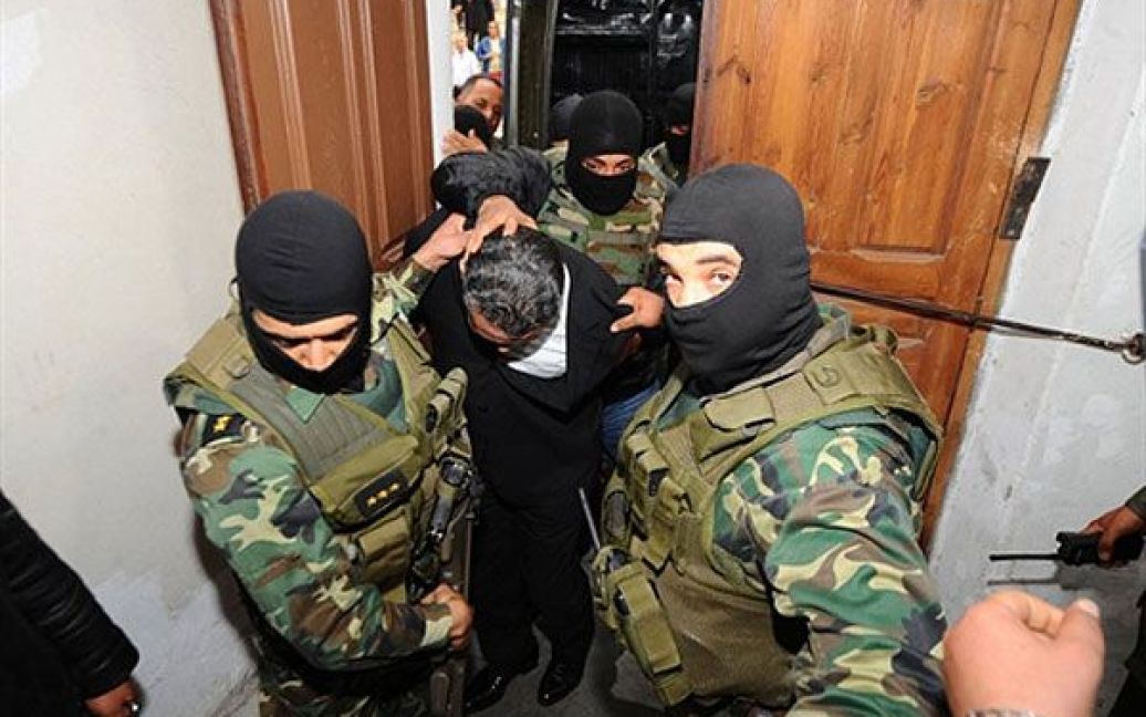 Туніс, Туніс. Сина колишнього президента країни Бен Алі Імеда Трабелсі співробітники сил безпеки ескортують до Палацу правосуддя в Тунісі. Сина екс-президента звинувачують у наркоторгівлі. / © AFP