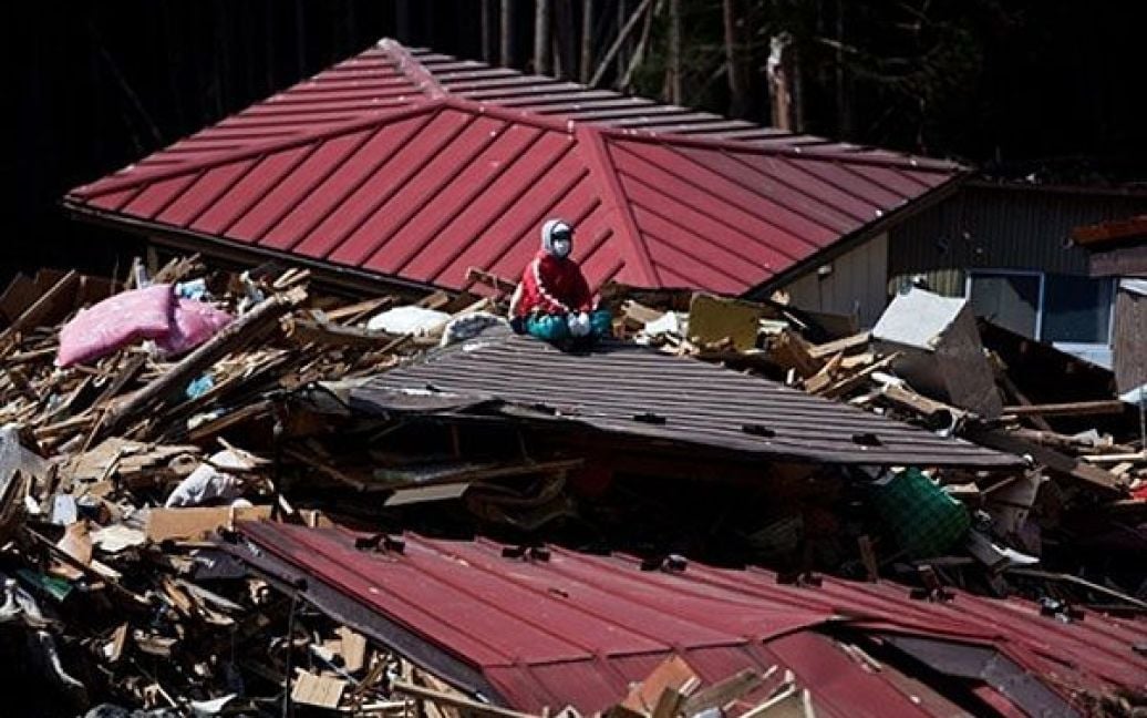 Японія, Мінамісанріку. Рибак Ютака Ватанабе сидить на даху свого зруйнованого будинку, доки він шукає зниклих членів своєї родини. Число загиблих і зниклих безвісті після руйнівного землетрусу та цунамі в Японії перевищило 28 тисяч осіб. / © AFP