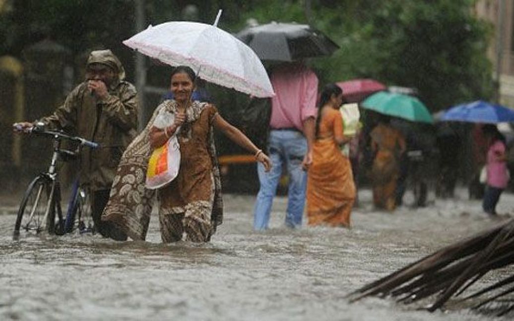 Індія, Мумбаї. Індійці переходять затоплену вулицю під час сильного дощу в Мумбаї. Сезон злив, який триває в країні з червня по вересень, має вирішальне значення для сотень мільйонів фермерів, а також для економічного зростання країни. / © AFP