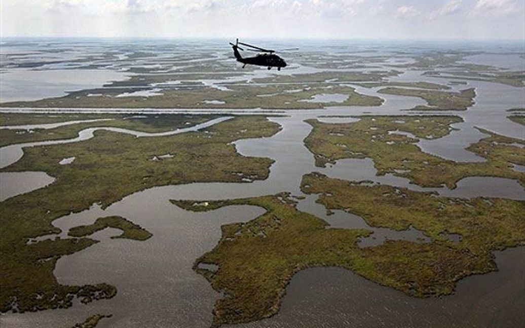 США, штат Луїзіана. Гелікоптер Blackhawk Національної гвардії Луїзіани пролітає над болотами. Через рік після катастрофічного розливу нафти з платформи ВР, узбережжя і пляжі ще вкриті мулом. Компанія BP стверджує, що більшу частину нафти було зібрано. / © AFP