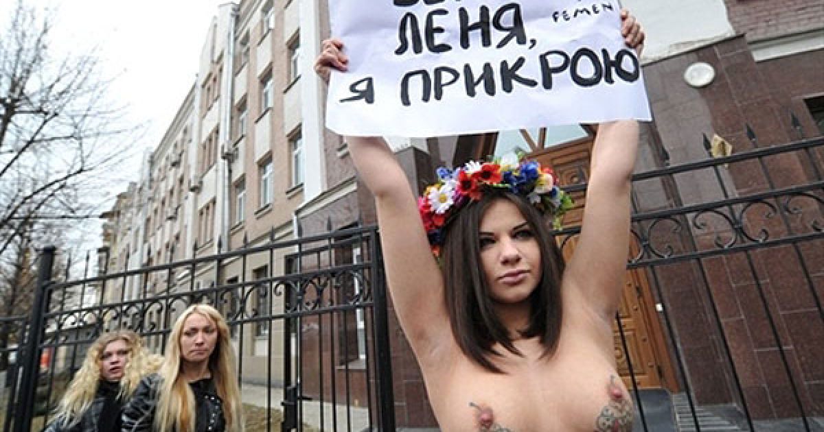 Україна, Київ. Активістка жіночого руху FEMEN тримає плакат із написом: "Біжи, Льоню, я прикрию" під час топлес-акції протесту перед будівлею Генеральної прокуратури у Києві, куди прибув на допит екс-президент України Леонід Кучма. / © AFP