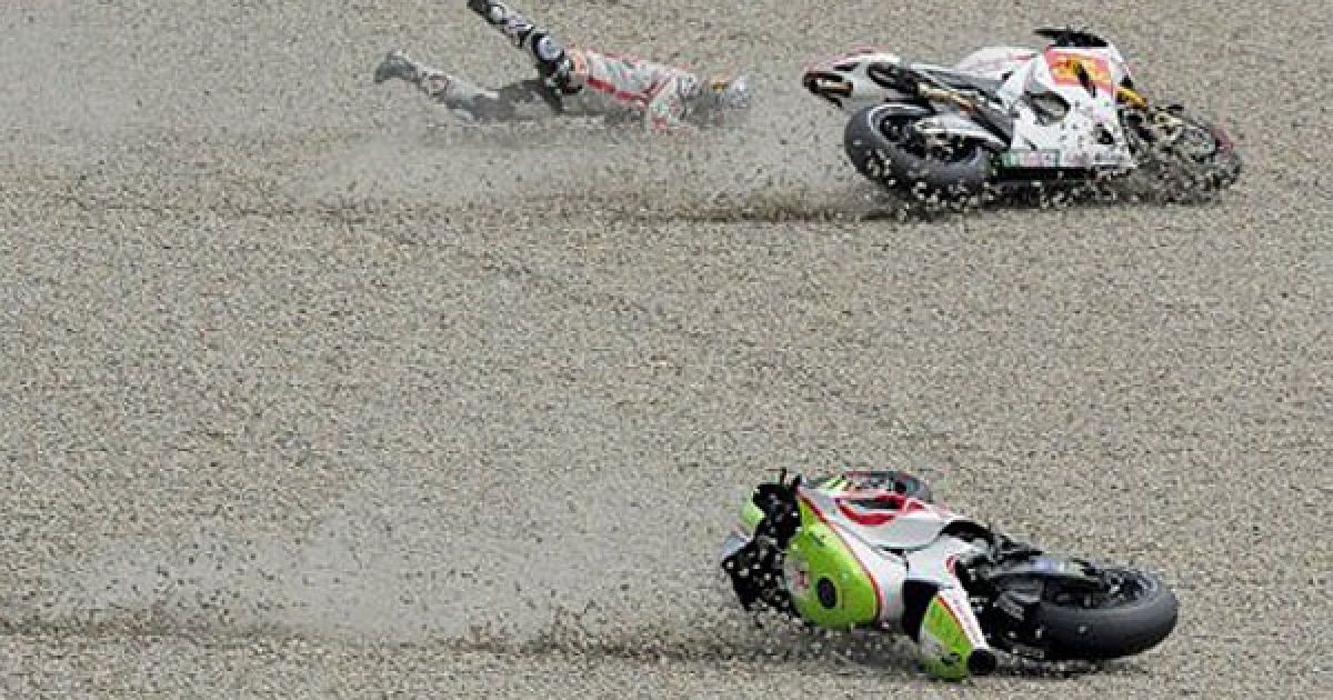 Іспанія, Монтемело. Французький гонщик команди "Pramac" Ренді де Пуне (не на фото) і японський мотогонщик команди "Honda" Хіросі Аояма падають під час виступу на гонці Moto GP в Каталонії. / © AFP