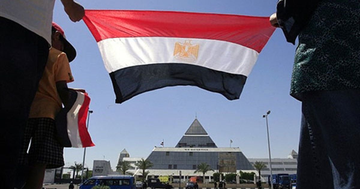 Єгипет, Шарм-ель-Шейх. Люди тримають прапор Єгипту перед лікарнею Шарм-ель-Шейх, до якої привезли колишнього президента Хосні Мубарака. Мубарак переніс серцевий напад під час допиту. / © AFP