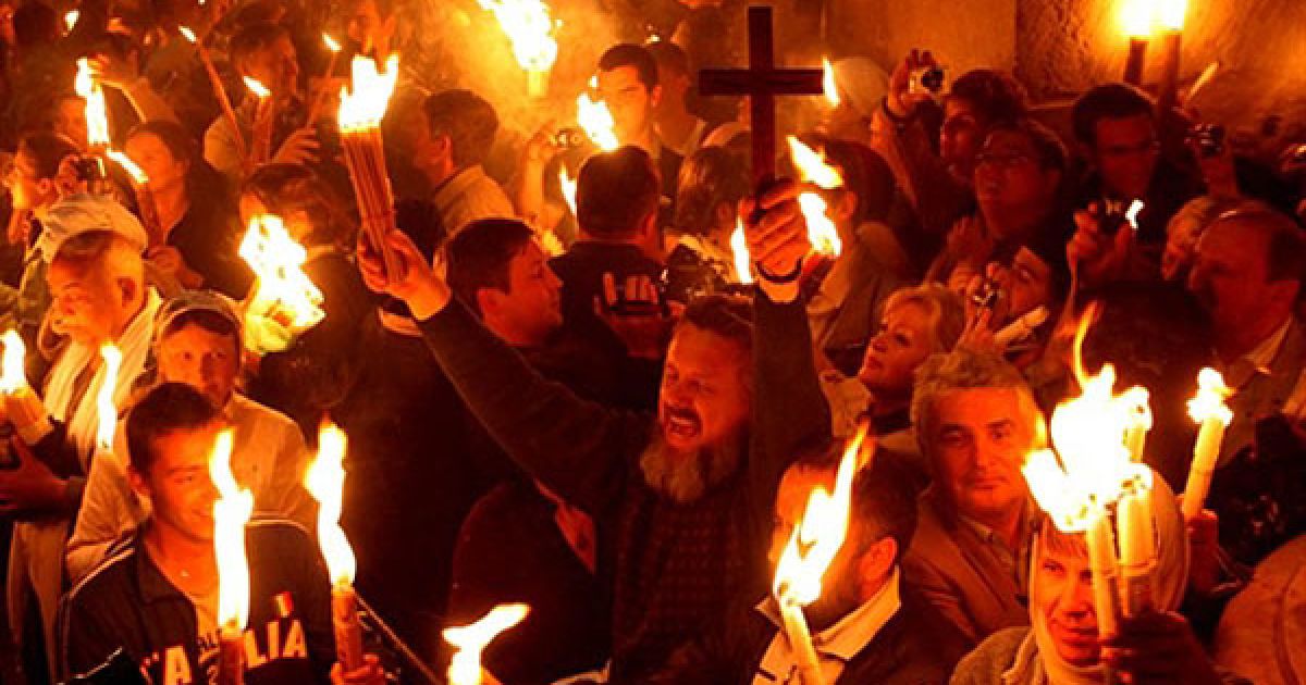 Єрусалим. Православні віруючі тримають свічки, запалені від "Благодатного вогню" під час церемонії у церкві Гробу Господнього в Старому місті Єрусалиму у переддень православного Великодня. / © AFP