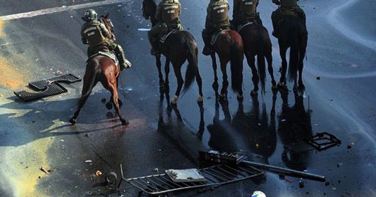 Чилі, Сантьяго. Кінні поліцейські зупиняють багатотисячний марш студентів, які провели акцію протесту проти уряду президента Себастьяна Піньєри та нового закону про освіту. / © AFP