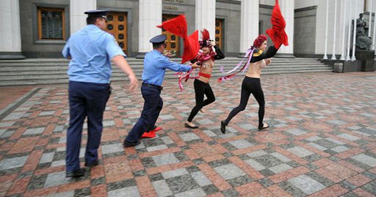 Україна, Київ. Міліціонери намагаються зловити активісток жіночого руху FEMEN, які влаштували перед будівлею Верховної ради топлес-протест проти підвищення пенсійного віку для жінок. Топлес-активістки FEMEN провели топлес-кориду під гаслом "Депутате, не бикуй!". / © AFP