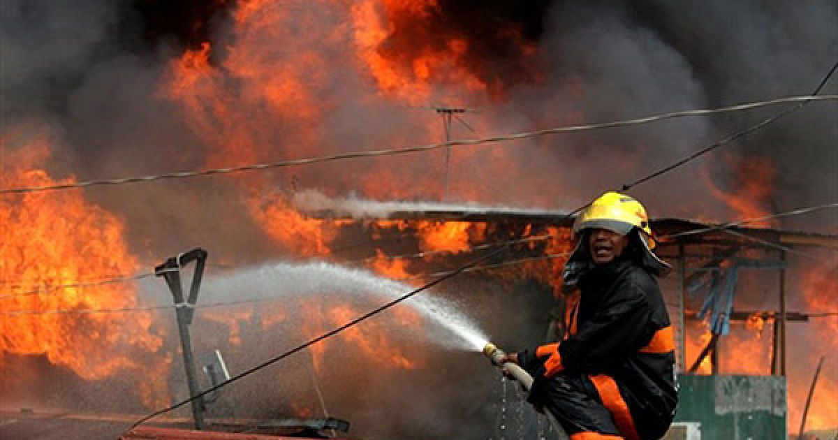 Філіппіни, Маніла. Пожежний намагається загасити вогонь під час сильної пожежі у нетрях фінансового району Маніли. Вогонь залишив без даху над головою понад 2000 сімей. / © AFP
