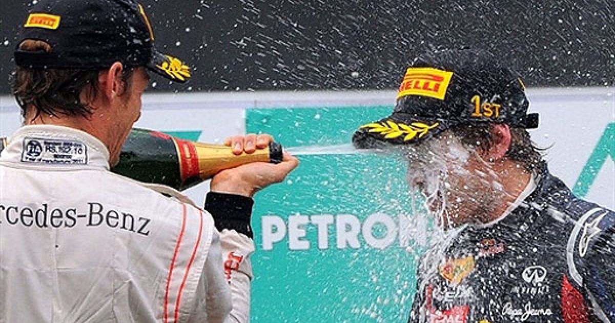 Малайзія, Сепанг. Гонщик McLaren-Mercedes Дженсон Баттон з Великобританії, який посів друге місце, поливає шампанським гонщика команди Red Bull-Renault Себастьяна Феттеля (Німеччина) під час нагородження переможців гонок Формула 1 на Гран-прі Малайзії. / © AFP