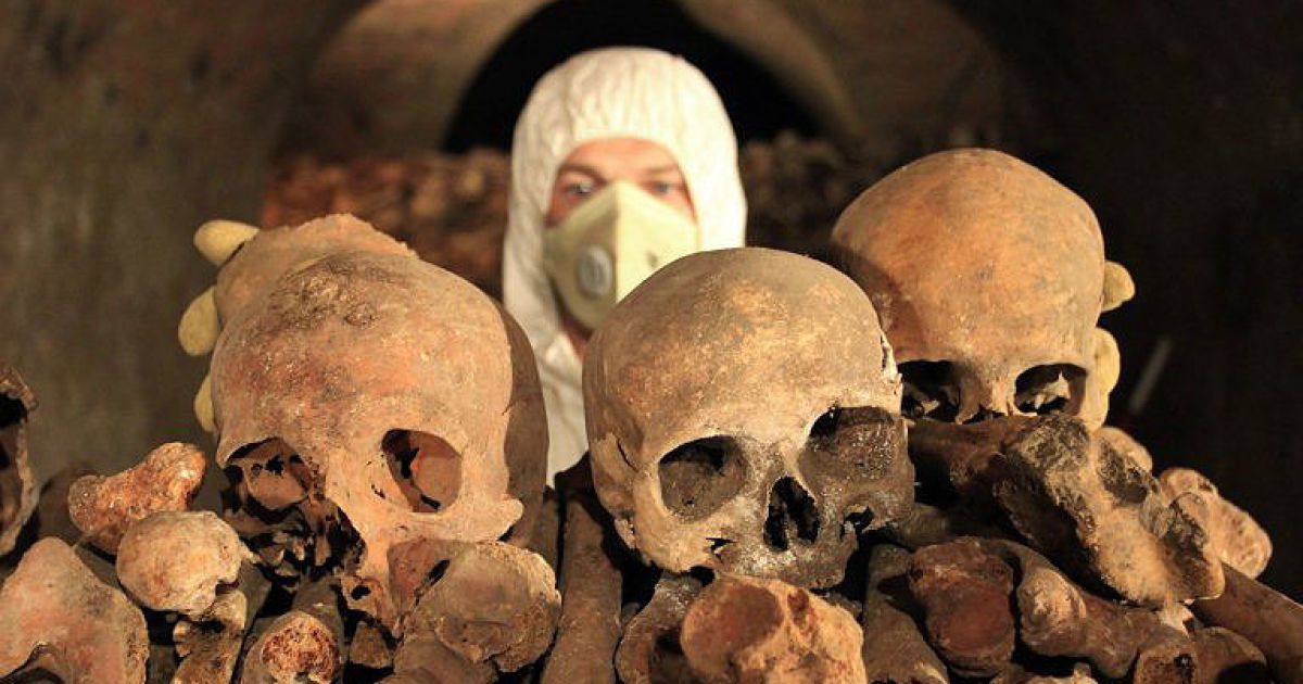 Чехія, Брно. Працівник у захисному одязі позує з черепами, які були знайдені в склепі під церквою Сент-Джеймс в історичному центрі Брно. Під площею знайшли близько 50 тисяч скелетів. Оссуарій є найбільшим сховищем кісток у Чехії та другим за величиною в Європі. / © AFP