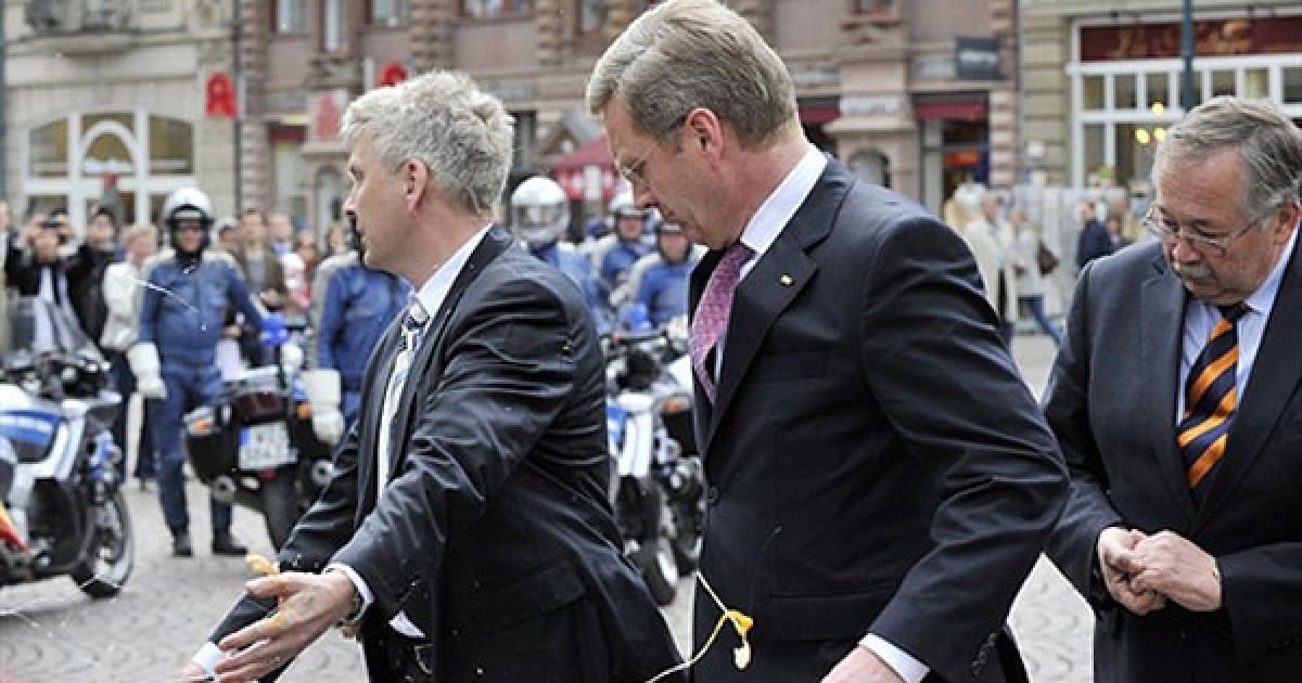 Німеччина, Вісбаден. Охоронець намагається закрити президента Німеччини Крістіана Вульфа, якого закидали яйцями під час візиту до міста Вісбаден, Західна Німеччина. / © AFP