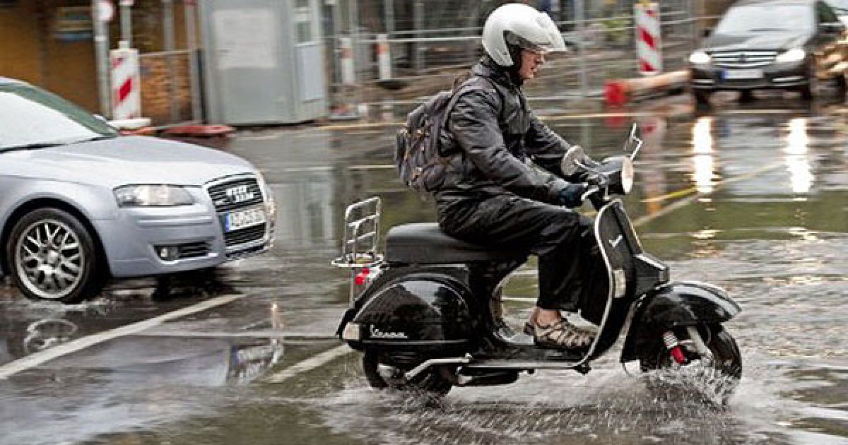 Німеччина, Берлін. Чоловік веде свій велосипед через залиту дощем вулицю в Берліні. Метеорологи прогнозують подальші опади у німецькій столиці. / © AFP