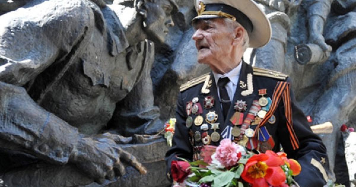 Україна, Київ. Ветеран Великої Вітчизняної війни стоїть поруч із монументом на честь Перемоги у війні під час святкування Дня Перемоги. / © AFP