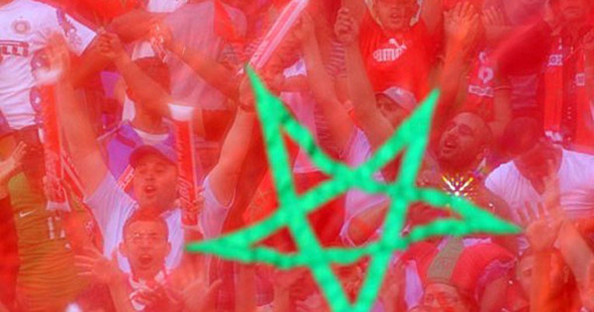 Марокко, Марракеш. Фанати марокканського футболу стоять за національним прапором під час футбольного матчу між Марокко та Алжиром на Кубок африканських націй 2012. Збірна Марокко перемогла з рахунком 4:0. / © AFP