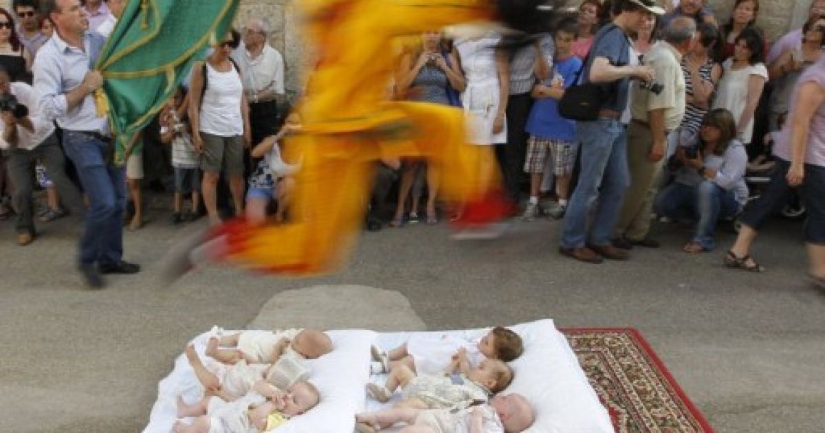 Іспанія, Кастрільо-де-Мурсія. Чоловік у костюмі диявола стрибає через немовлят, які лежать на матраці, під час святкування "Ель Colacho". Стрибки через дітей є традиційним іспанським ритуалом, який виконують, починаючи з 1620 року, на честь католицького свята Тіла Христового. / © AFP